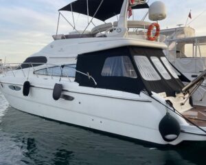 2007-cranchi-atlantique-50-power-10134266-20260331182318768-1 | Boat Universe White motor yacht docked at a marina with black cockpit canvas and covered windows; calm water around it and other boats in the background.