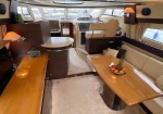 Luxurious yacht interior with cream seating, wood table, and fruit bowl in a marina-view salon