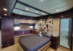 Luxurious bedroom on a yacht with dark wood cabinetry, a large bed, decorative partition, and an en suite bathroom door nearby