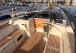 Sailboat cockpit at a marina with coiled lines and teak deck planks visible.