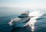 White luxury motor yacht speeding across calm blue ocean with sparkling wake and distant horizon.