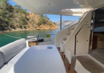 Deck of a luxury yacht with a long white table, cushioned seating, and a clear ocean view of rocky cliffs.](https://example.com)