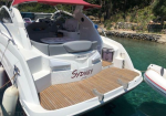 Rear view of a white luxury motorboat with a wooden deck, pink canopy, and 'Sydney' on the stern, docked in clear turquoise water.