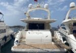 Rear view of a white luxury yacht named Graper docked at a marina, with teak deck and neighboring boats on either side.