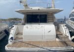 Back view of a white luxury yacht named 'Grape' docked at a marina, showing teak deck and stern stairs on both sides.