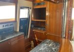 Luxurious yacht galley with dark marble countertops, wood cabinets, and a sink area on the left.