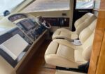 Leather captain's chair and beige cockpit with steering wheel and navigation panel of a luxury yacht