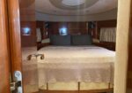 Luxurious boat cabin bedroom with a made bed, dark pillows, and wooden paneling on both sides.