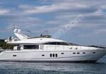 White luxury motor yacht cruising on calm blue water under a partly cloudy sky