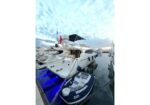 Luxurious white motor yacht docked at a marina with a blue-lit swim platform and a small navy inflatable dinghy tied alongside.