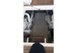 Open hatch shows a yacht engine compartment with two white engines and beige deck liner.