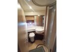 Small bathroom with a rounded sink, toilet, and curved glass shower door, plus wood cabinets and a mirror. (compact vanity area)