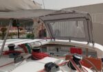 Sailboat cockpit with winches, red and green lines coiled, and a raised canopy over the deck.