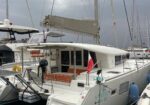 White Lagoon catamaran docked in a marina, with orange cushions in the cockpit and a folded mainsail on the boom.