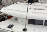 White catamaran deck at a marina, with lines, rails, and a Lagoon logo visible on the cabin.