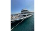 White multi-deck passenger boat named 'Sultania' docked at a pier on calm blue water under a clear sky.