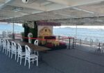 Wedding or event setup on a boat deck with an ornate gold throne, red velvet cushions, and floral backdrop overlooking the water.
