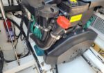 Marine engine bay with a red capped dipstick/oil cap, coolant reservoir labeled Volvo, and black hoses connected to the engine