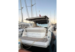 White motor yacht named Therapia London docked at a marina with ropes and masts in the background (rear view).