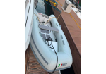 Inflatable dinghy secured to a dock, with a small solar panel and cables inside the boat's cockpit area.
