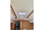 Wood-paneled boat cabin interior with a rectangular skylight in the ceiling and a small bed area visible.