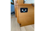 Wooden boat cabin corner with a small black control panel featuring two gauges and a central knob mounted on the side.
