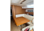 Wood-paneled boat cabin with a rectangular wooden table and cream cushioned bench seating along two walls.