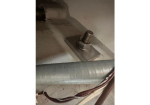 Anchor bolt with washer fixed to a metal base plate, with a curved duct and exposed wiring nearby.