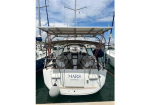 Rear view of a white sailing yacht named 'MARS' docked at a marina, twin steering wheels, cockpit seating, and a solar panel-covered bimini top.