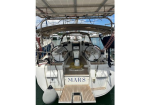 Rear view of a white sailboat named MARS docked in a marina, showing dual steering wheels, cockpit seating, and a wooden swim platform at the stern.