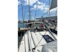 View from the cockpit of a white sailboat docked at a marina, masts and rigging rising against a blue sky.