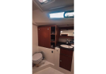 Boat bathroom with a wooden cabinet, sink, mirror, and a toilet on a yacht interior.