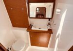 Compact yacht bathroom with a white sink, wooden cabinetry, and a mirror above the counter.