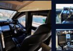Captain’s helm inside a luxury yacht: leather chair, steering wheel, gauges, and navigation screens, with a marina outside.