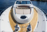 Front deck of a white luxury yacht with teak wood flooring and a seating area at the bow.