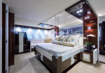 Luxurious yacht cabin bedroom with a large white bed, decorative pillows, dark wood nightstands, and mirrored ceiling panels.
