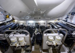 Interior of a ship engine room with two large diesel engines, metal rails, and an array of pipes and valves.