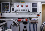 Control panel on a vessel wall with three large red emergency stop buttons, switches, and a digital readout; hoses and wiring visible behind.