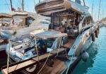 Large modern motor yacht docked at a marina, with an open aft deck and a small white dinghy mounted on a davit.