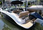White and blue motorboat docked at a marina with beige seating and a black canopy over the cockpit.