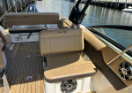 Beige Sea Ray boat cockpit with cushioned seating, wooden deck, and water at the dock