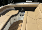 Beige cushioned boat seating with a hexagon-pattern panel, chrome speaker, and wooden deck beneath; cup holders in the center console area.