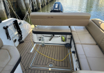 Boat cockpit with beige cushioned seating and teak-style deck, engine visible at stern.