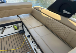 Beige boat seating with honeycomb stitching, teak-style deck, and a yellow power cord plugged into a round outlet near a storage hatch.