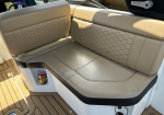 Beige boat bench seat with honeycomb-stitched backrests and wood deck flooring nearby.