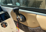 Close-up of a boat throttle lever mounted on a beige perforated dashboard, with keys and tag hanging nearby.