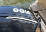 Close-up of a black Mercury outboard motor with a large white 300 decal, mounted on a boat by the water.