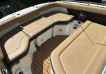Tan cushioned seating area on a boat with a cooler tucked under the seat and a wood-pattern deck