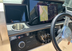 Boat cockpit with a SIMRAD navigation display, steering wheel, and control panel at the helm.