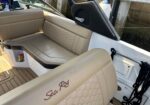 Beige cushioned seating area inside a Sea Ray boat, honeycomb-patterned upholstery and wood deck flooring